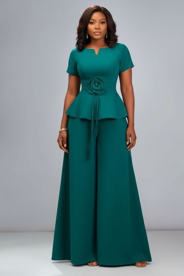 Woman wearing a teal peplum top and long skirt set on a gray background